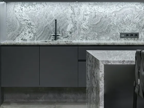 Graphite drawer fronts with a recessed pull channel beside a marble waterfall island.