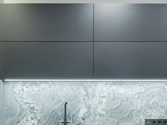Graphite upper doors over a lit marble backsplash.