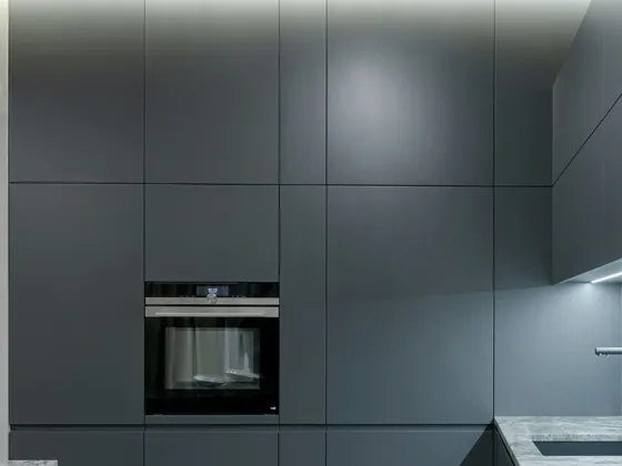 A wall of tall graphite cabinets with a built-in oven, turning the corner into the sink run.