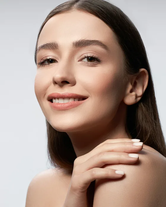 A client smiling, her skin clear and even, one hand resting on her shoulder