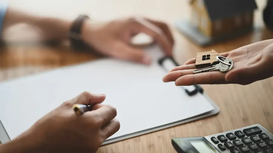House keys handed across a desk while the paperwork is signed