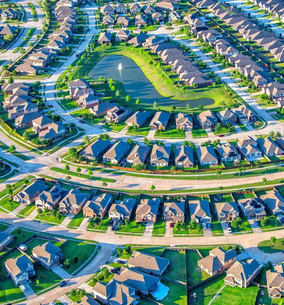 From the air: streets of detached homes curving around a pond
