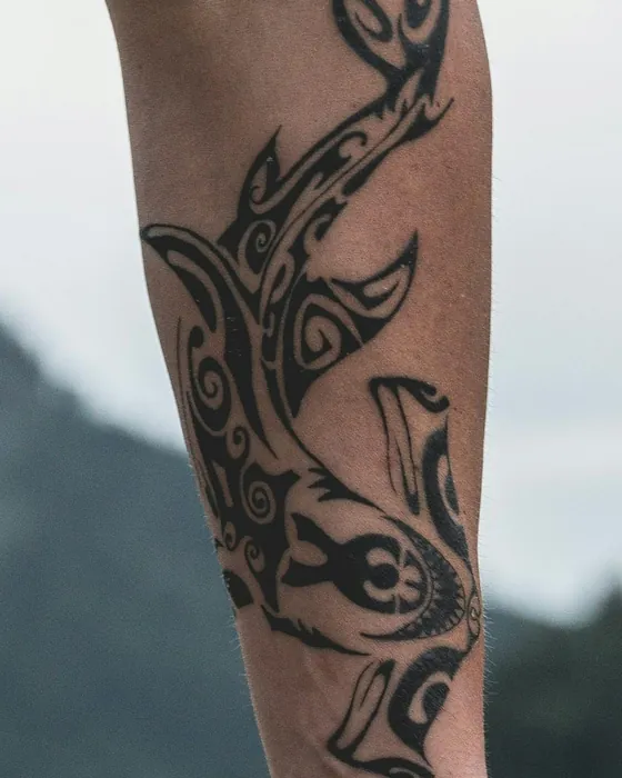 A bold black hammerhead shark in Polynesian-style blackwork on a forearm
