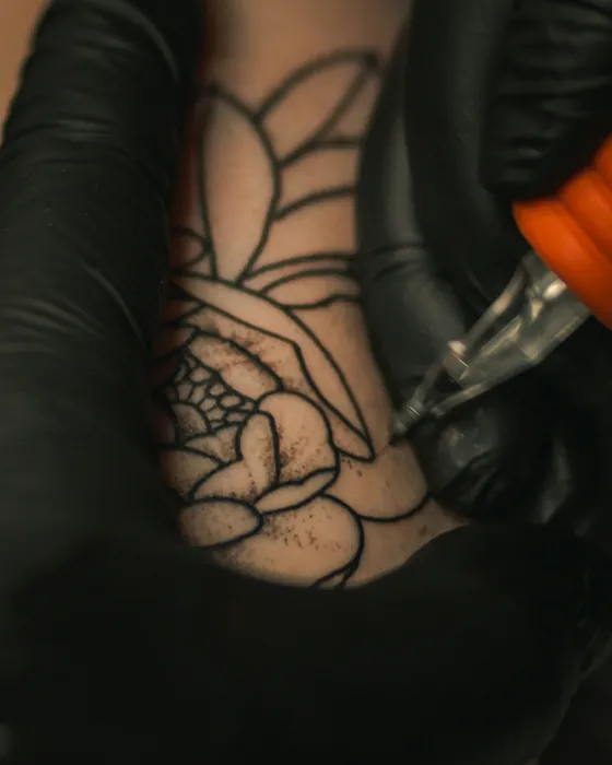An open rose being lined in black on an upper arm